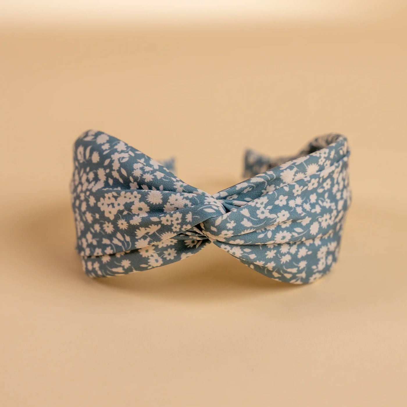 Lucys blue and white simple floral headband. Light blue background with simple white floral pattern. Front view. 