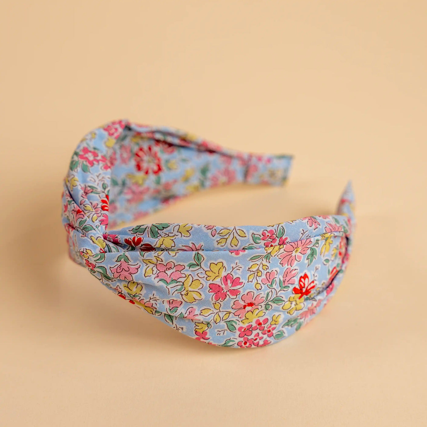 Lucys Light Blue Poppy Floral Headband. Light blue background with pink, yellow, and red flowers. Side view.