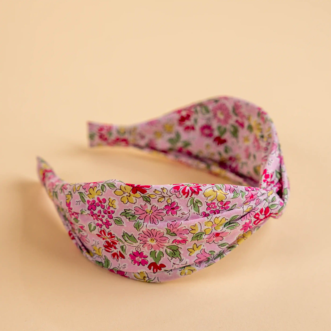 Lucys Pink Poppy Floral Headband. Light pink background with pink and yellow flowers. Side view.