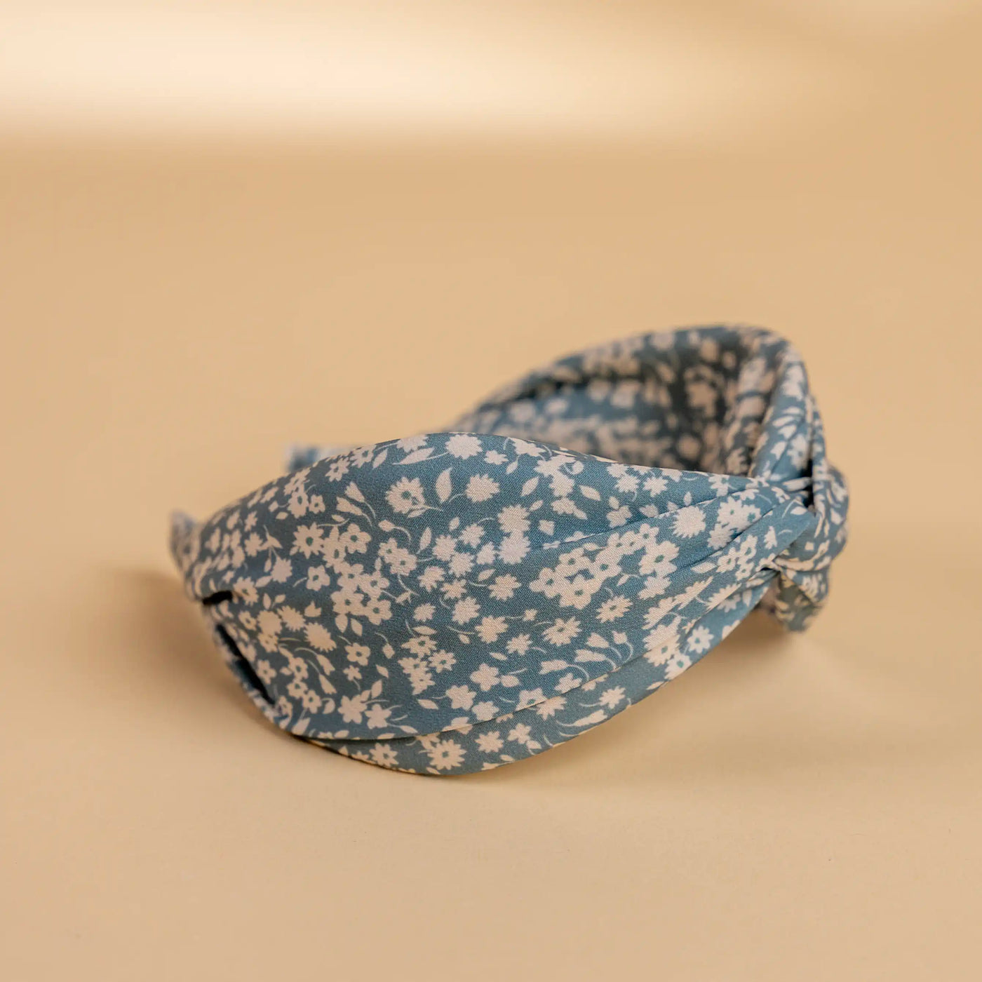 Lucys blue and white simple floral headband. Light blue background with simple white floral pattern. Side view.