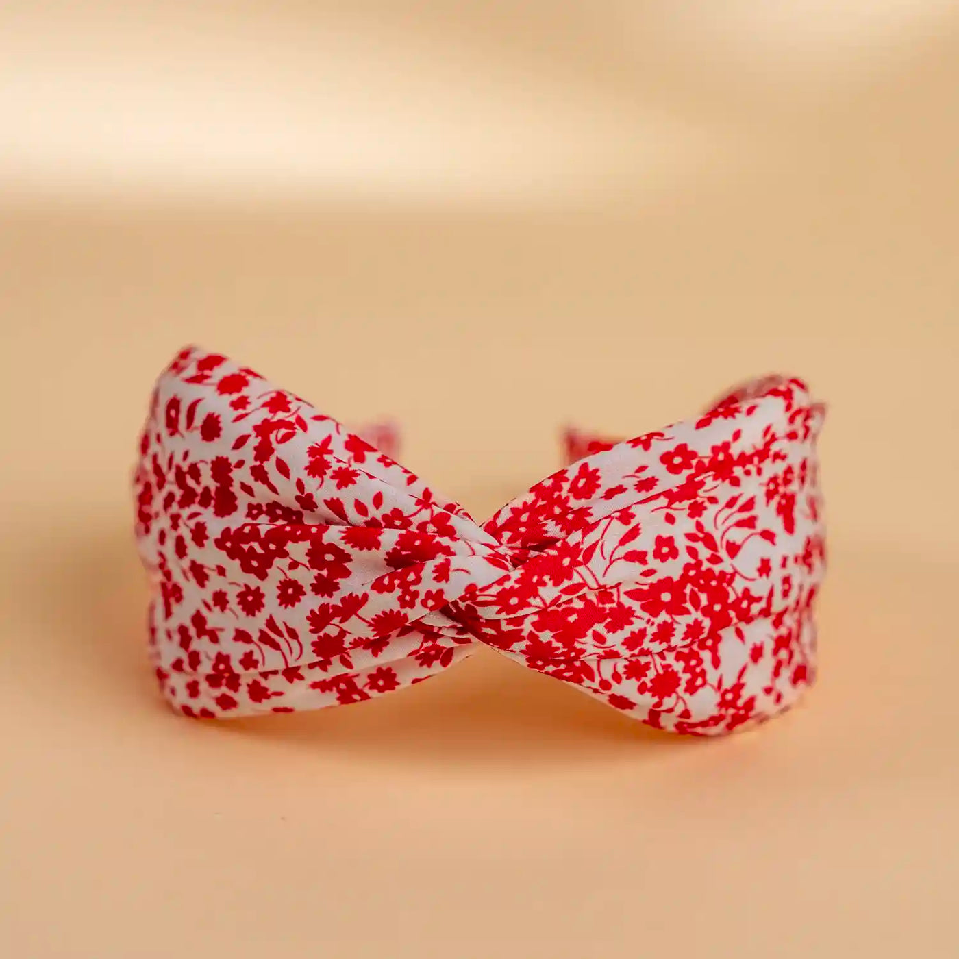 Lucys red and white simple floral headband. White background with simple red floral pattern. Front view.