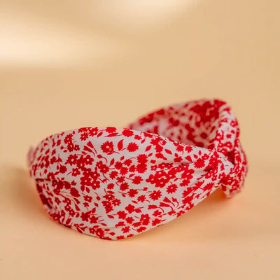 Lucys red and white simple floral headband. White background with simple red floral pattern. Side view.