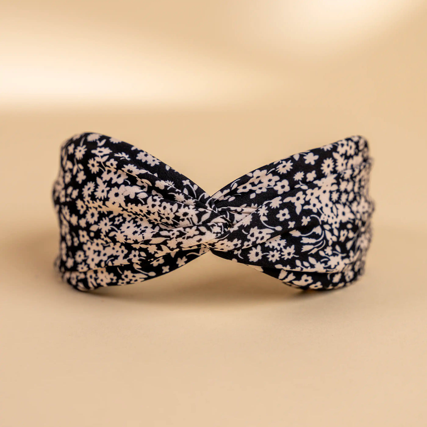 Lucys black and white simple floral headband. Black background with simple white floral pattern. Front view.