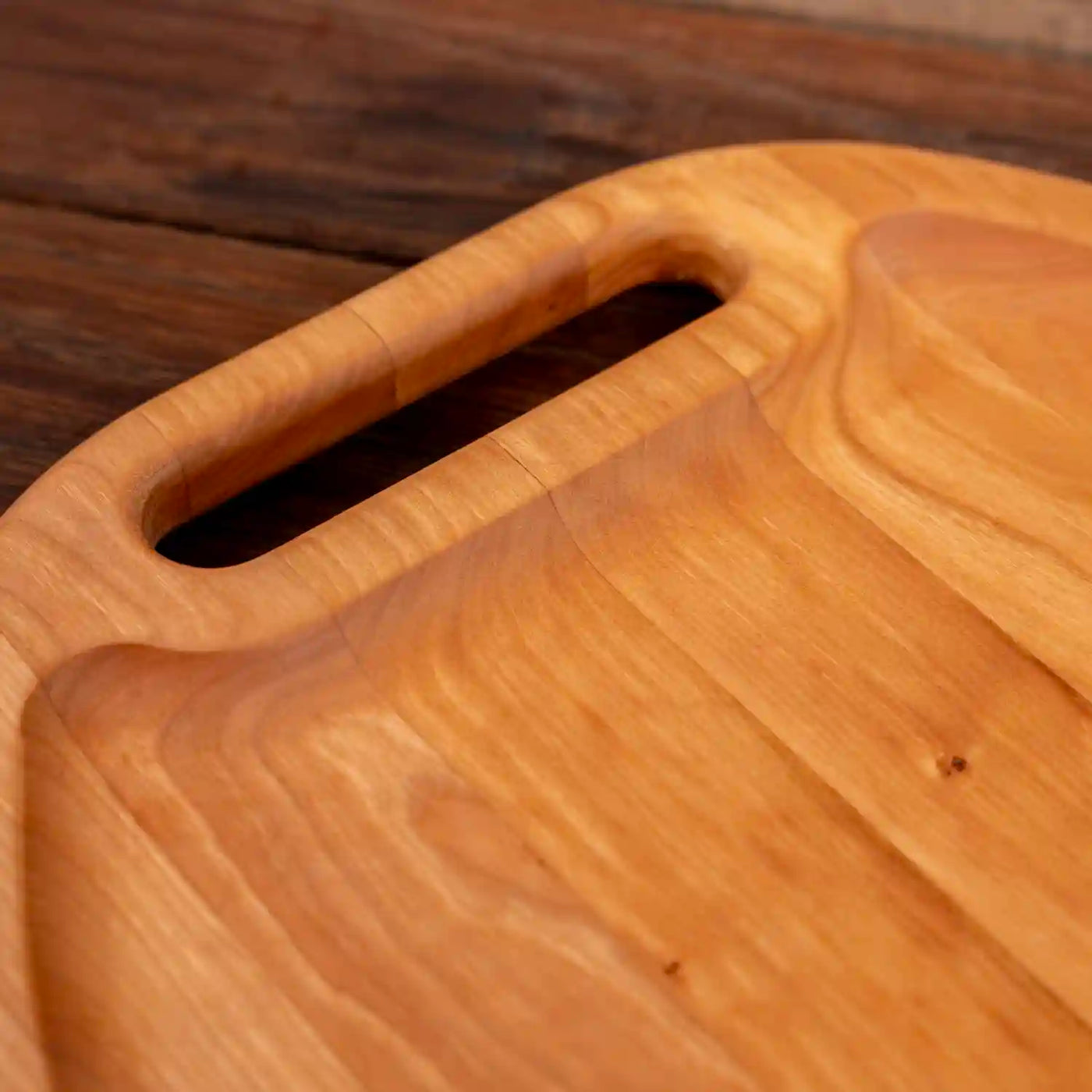Cherry Oval Barbecue Board. Close up of handle and raised edge. 