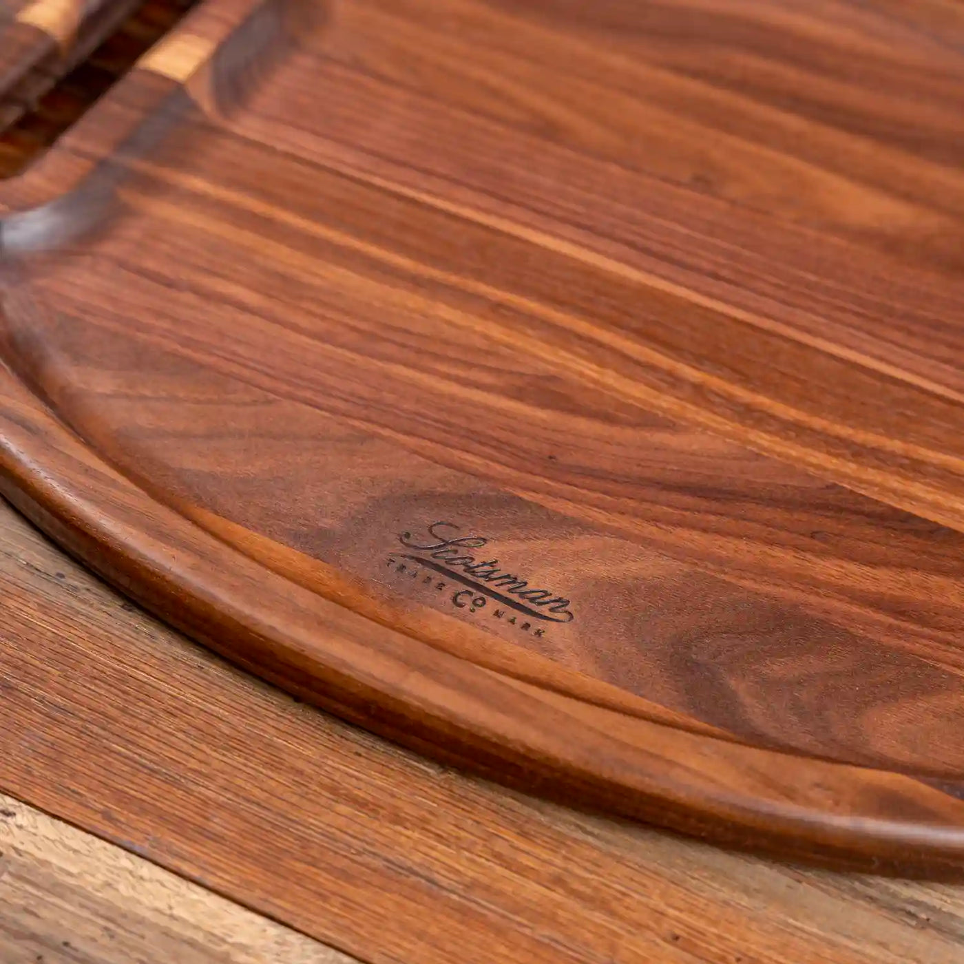 Walnut Oval Barbecue Board.  Close up of Scotsman logo and raised edge.