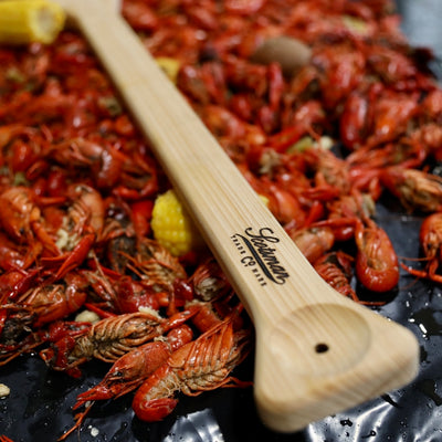 Cypress crawfish paddle. Close of handle and tasting spot. Laying on a pile of crawfish. 